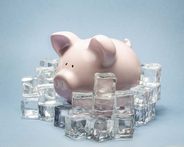 piggy bank surrounded by ice cubes symbolizing a pay freeze