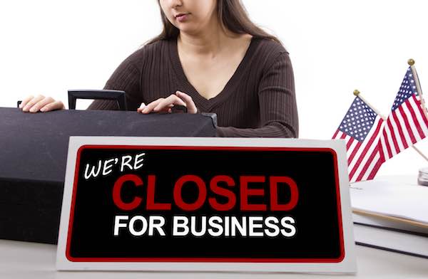 woman with a desk sign showing closed for business depicting a government shutdown