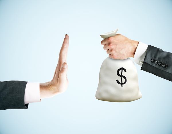 Hand of one businessman raised in a stop gesture towards the extended hand of another businessman holding a bag of money depicting refusing payment