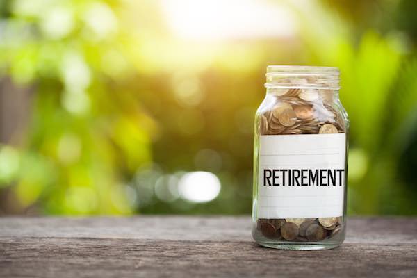 glass jar filled with coins labeled 'retirement' depicting saving for the future