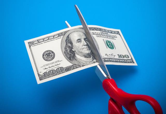 Scissors cutting a $100 bill