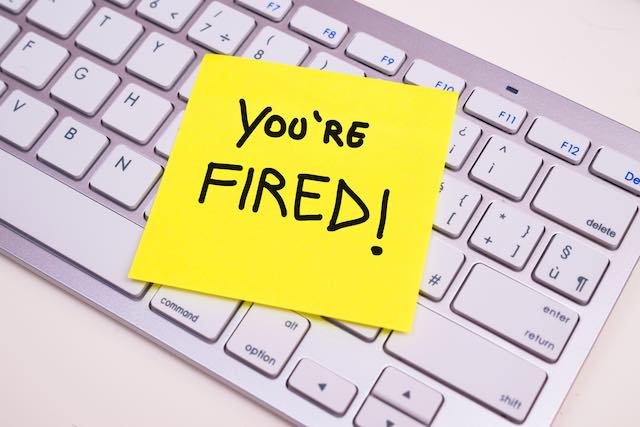 Yellow post it note with words 'you're fired!' stuck to a keyboard