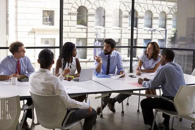 Group of employees in an office setting negotiating around a conference room table