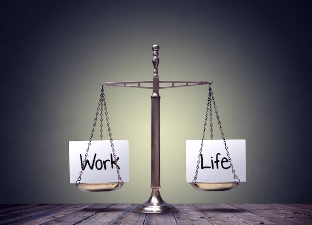 Balanced scale with a card labeled 'work' on one side and a card labeled 'life' on the other indicating a work-life balance