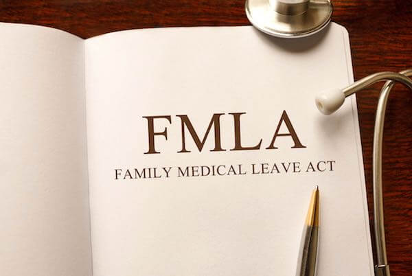 Book on table with pen and stethoscope open to a page that reads 'FMLA Family Medical Leave Act'