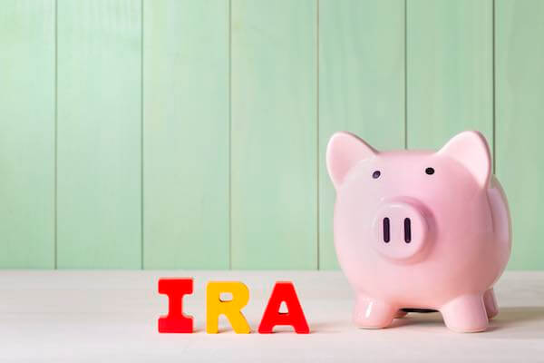 Pink piggy bank next to the letters 'IRA' depicting saving for retirement