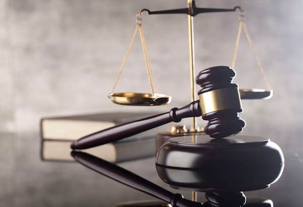 Judge's gavel on a desk with justice scales and a law book in the background