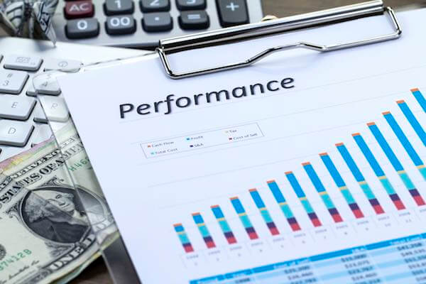 Financial chart labeled 'performance' sitting on a desk next to cash and a calculator depicting pay for performance