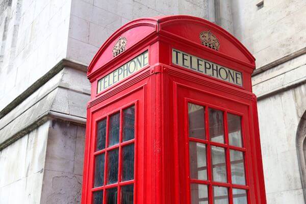 Closeup of the top of a phone booth pictured next to a city building