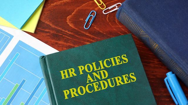 Book on a desk labeled 'HR Policies and Procedures'