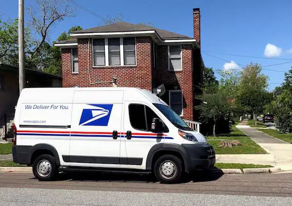 Postal Service delivery truck parked in front of a house