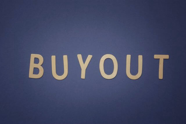 Wooden letters spelling 'buyout' on a solid blue background