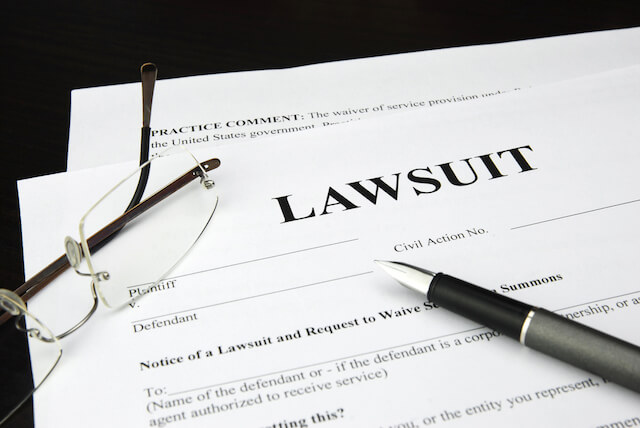 Document labeled 'lawsuit' sitting on a desk with a pen and glasses