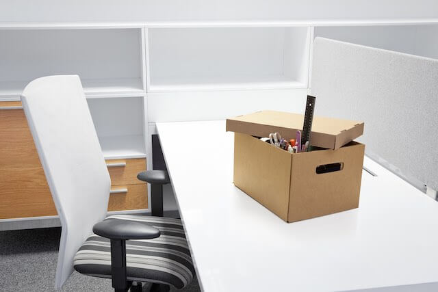 Empty employee desk with a box of personal belongings sitting on top of it depicting RIF/layoff/workforce reductions among federal employees and/or the federal workforce