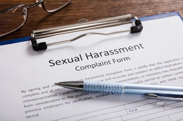 Close up of a document on a desk labeled 'sexual harassment complaint form' with a pen on top