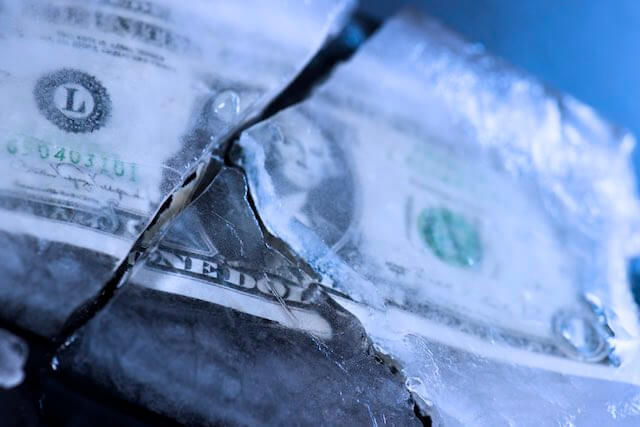 One dollar bill frozen in a block of cracked ice depicting a pay freeze/no raise