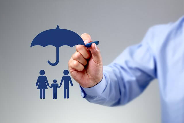 Businessman's hand holding a pencil drawing a sketch of an umbrella over 3D icons of a man, woman and child depicting FEHB family health insurance