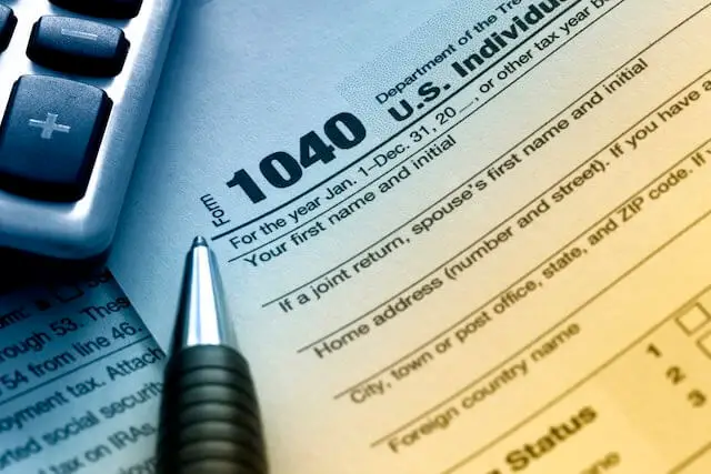 Image of the top left of IRS form 1040 individual income tax form with a pen and calculator