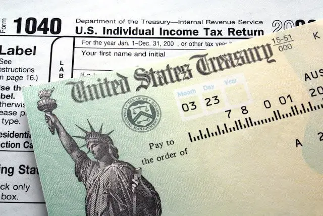 United States Treasury check pictured on top of IRS form 1040 depicting a tax refund from the IRS