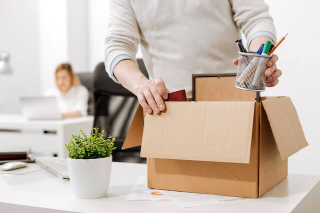 Employee packing personal belongings at his workstation into a box as he prepares to leave his job after being fired/resigning