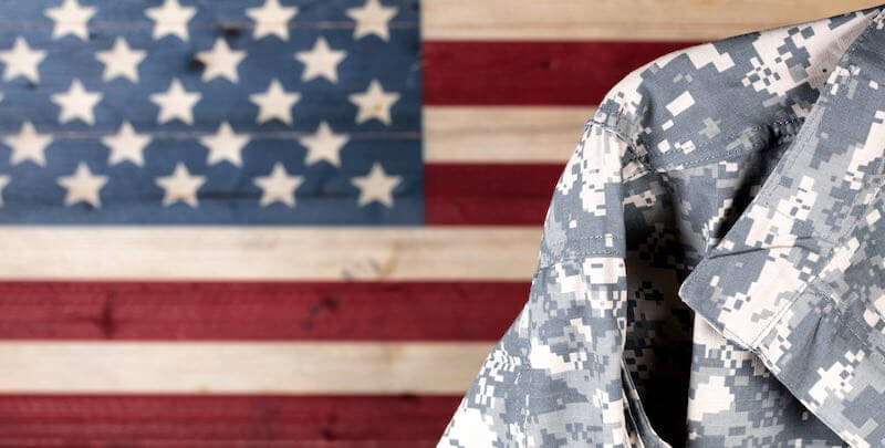 Close up of a military service member's uniform pictured over an American flag in the background