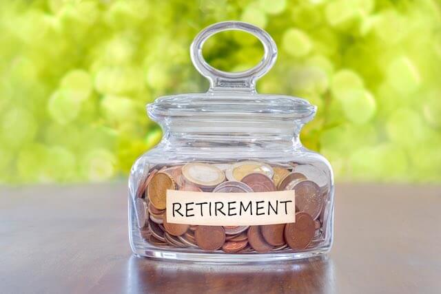 Coins in a jar labeled 'retirement' depicting saving for retirement