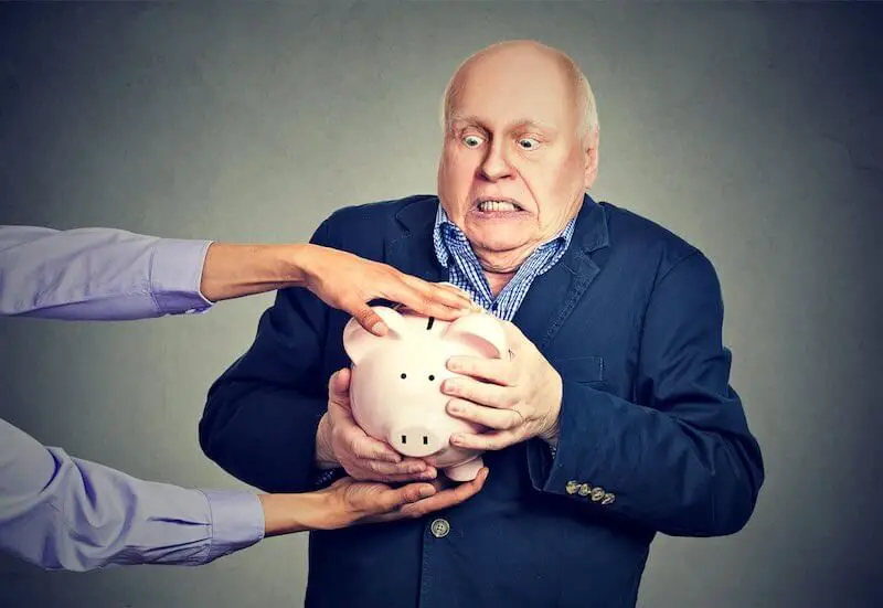Middle aged businessman clutching a piggy bank tightly as the hands of another businessman are trying to take it away from him depicting theft/taking away retirement/pension plans