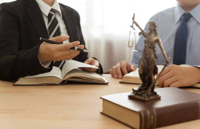 Two businessmen sitting at a conference room table with open books engaged in a negotiation