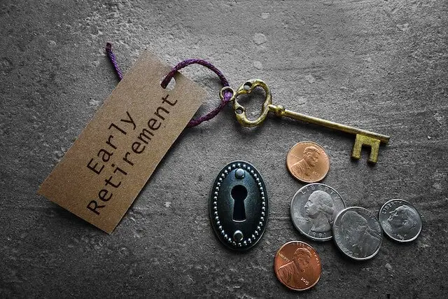 Old style key with a keychain labeled 'early retirement' sitting next to a keyhole and some coins