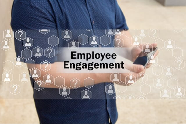 Image of an employee holding a smartphone overlaid with the words 'employee engagement' along with a collage of icons depicting the human resources/federal workplace environment/process