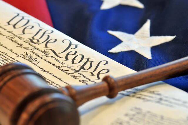 Judge's gavel sitting on top of a copy of the Constitution and an American flag