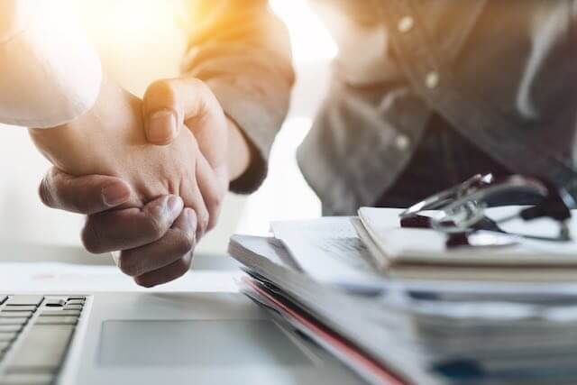 Close up of two businessmen' hands engaged in a handshake indicating a settlement agreement