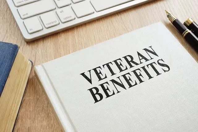 Booklet sitting on a desk labeled 'veteran benefits' in front of a computer keyboard with a pen lying next to it