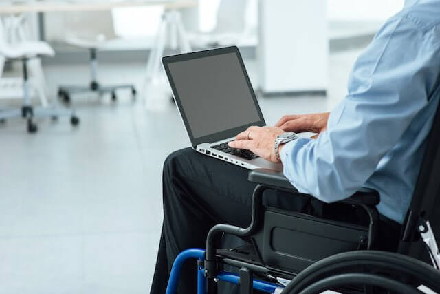 Closeup of a businessman sitting in a wheelchair working on his laptop