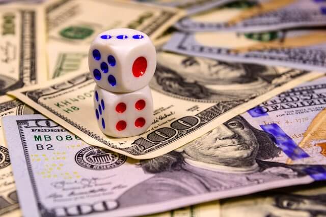 Two dice sitting on top of a spread of cash depicting casino gambling