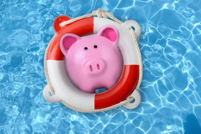 Pink piggy bank inside of a lifeguard's rescue buoy floating in a swimming pool