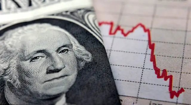 Close up of the face of a $1 dollar bill next to a red financial line chart showing stock market declines