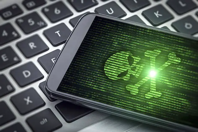 Image of a skull and crossbones on a smartphone screen sitting on top of a computer keyboard depicting virus/malware/phising/hacking via a cybersecurity breach