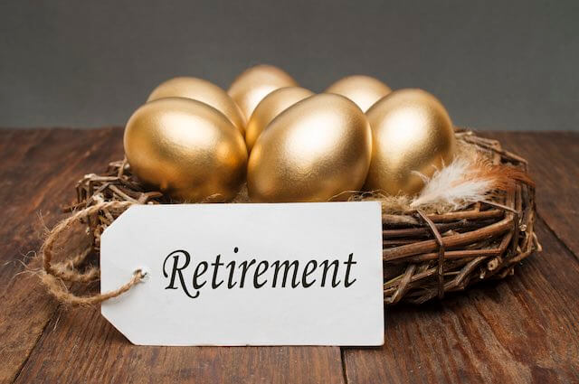 Group of golden eggs sitting inside of a bird's nest with a tag attached that reads 'retirement' depicting a solid retirement nest egg and long-term savings plan