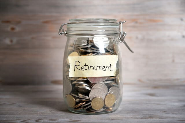Glass jar labeled 'retirement' against a wooden background depicting retirement savings/investing