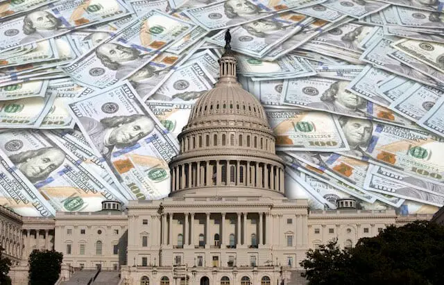 US Capitol building in Washington, DC with a scattering of $100 bills pictured behind it depicting government spending