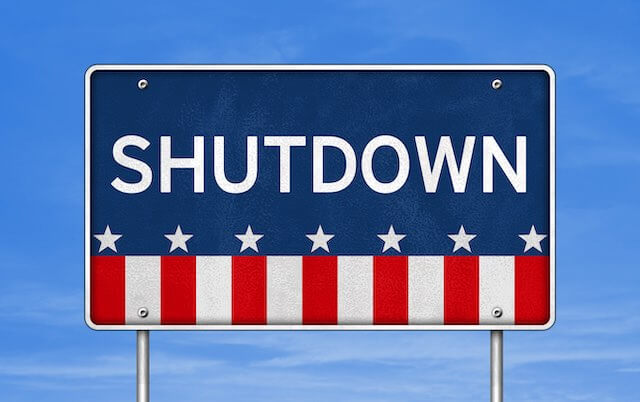 Word 'shutdown' written on a road sign with an American flag design