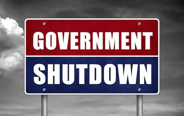 Sign that reads 'government shutdown' pictured against a cloudy grey background