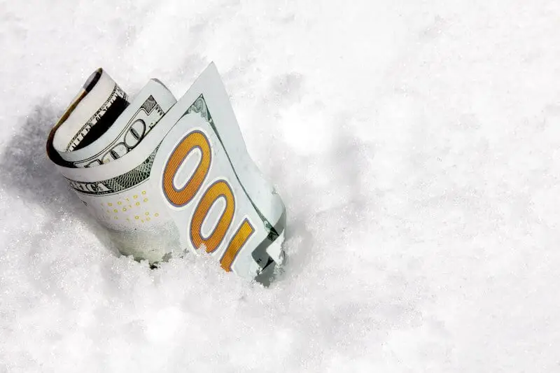 Rolled up $100 bill stuck in snow and ice depicting a pay freeze for federal employees