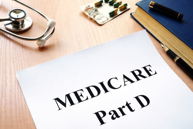 Paper on a desk labeled 'Medicare Part D' next to a stethoscope and packet of pills