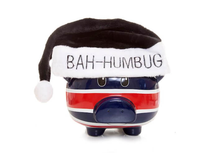 Blue and red striped piggy bank wearing a black Santa hat that says 'bah humbug'