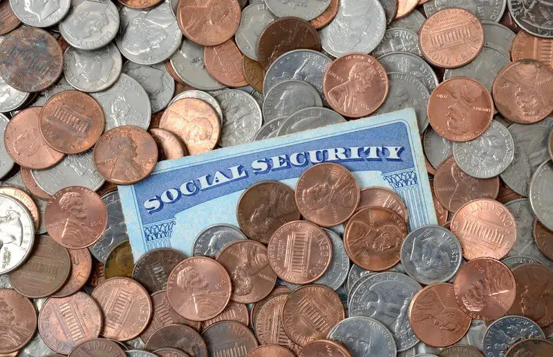 Social Security card partially obscured from being underneath a scattering of coins