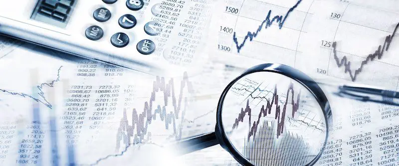 Stock Quotes as graphs and tables with magnifying glass focused on a graph showing stock market volatility and calculator in panoramic format