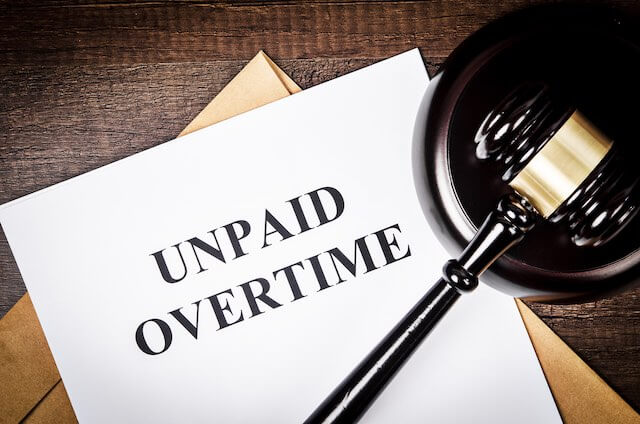 Document on a desk labeled 'unpaid overtime' next to a wooden judge's gavel