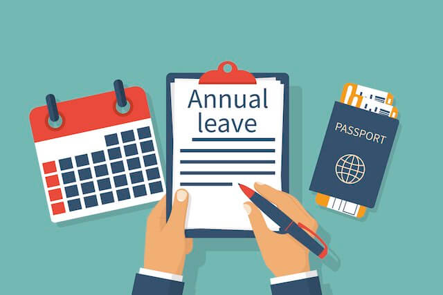 Illustration of a person writing on a notepad labeled 'annual leave' at the top with a passport and calendar on a desk next to it